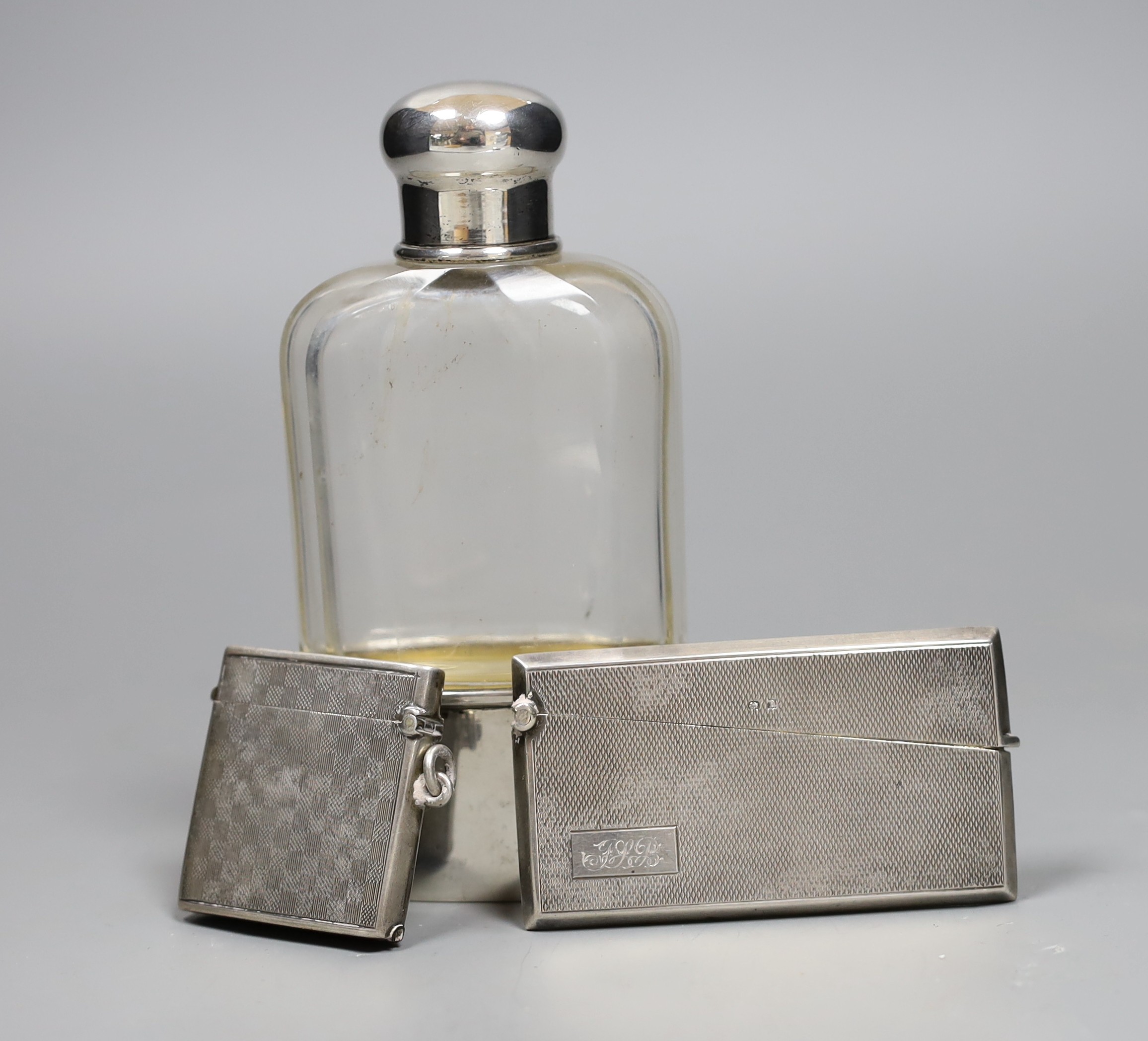 A German 800 standard white metal mounted glass hip flask, 14cm, a George V silver vesta case and a 1920's engine turned silver card case.